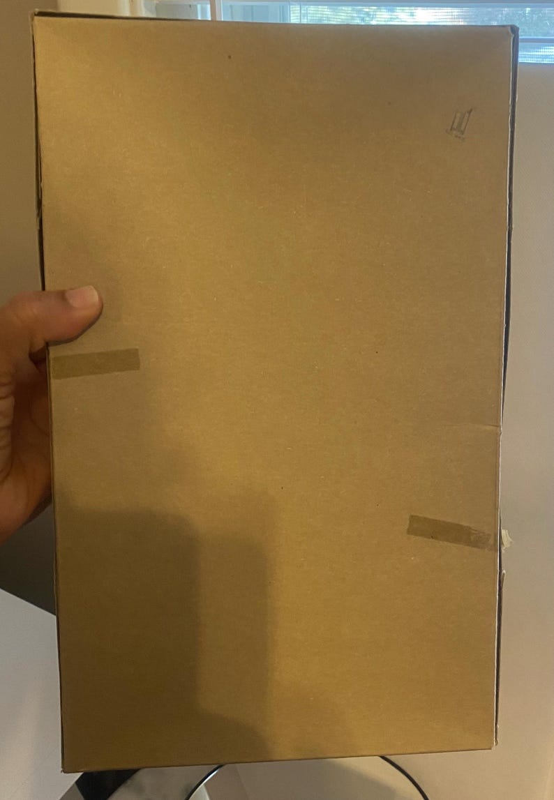May include: A plain brown cardboard box with tape on the sides. The box is sealed and ready for shipping.