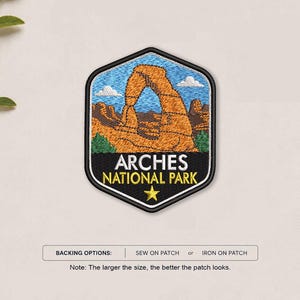 May include: A hexagonal embroidered patch featuring a depiction of Delicate Arch in Arches National Park. The design includes orange rock formations, a blue sky with white clouds, and green foliage. The text reads ARCHES NATIONAL PARK with a yellow star.