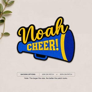 May include: An embroidered patch shaped like a blue megaphone with a yellow border and yellow text that reads Noah CHEER!. The patch features a black outline and includes text below stating BACKING OPTIONS: SEW ON PATCH or IRON ON PATCH.