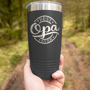 May include: A dark gray stainless steel tumbler with a silver inscription that reads "Best Opa Ever" in a circle with stars.