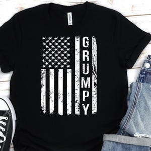 May include: Black t-shirt with a white distressed American flag design and the word "GRUMPY" printed vertically on the right side of the flag.