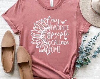 May include: A dusty rose t-shirt with a white sunflower graphic and the text "my favorite people call me OMI".