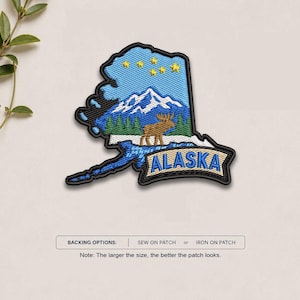 May include: An embroidered patch shaped like the state of Alaska, featuring a light blue sky with yellow stars, white snow-capped mountains, green pine trees, and a brown moose. A banner at the bottom displays the text ALASKA in blue letters.