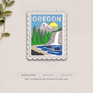 May include: A rectangular embroidered patch shaped like a postage stamp featuring the word OREGON in white text. The design depicts a mountain, green pine trees, a waterfall, a blue river, and a yellow sun. Backing options include sew-on or iron-on.