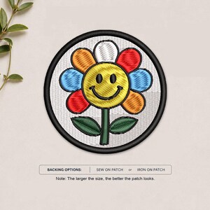 May include: A circular embroidered patch featuring a yellow smiley face flower with multi-colored petals in red, orange, blue, and white, set against a white background with a black border. Text reads: BACKING OPTIONS: SEW ON PATCH or IRON ON PATCH.