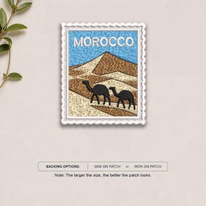 May include: A rectangular embroidered patch with a scalloped white border featuring a desert landscape with two black camels and the word MOROCCO in white text against a blue sky. Below the patch, text reads BACKING OPTIONS: SEW ON PATCH or IRON ON PATCH.
