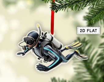 May include: A 2D flat Christmas ornament featuring a scuba diver in a black wetsuit with teal accents. The ornament has a red ribbon for hanging and the name "DANIEL" is visible. The diver is wearing a mask, snorkel, and fins.