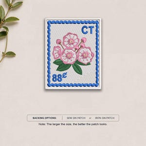 May include: A rectangular embroidered patch designed like a postage stamp with a white background and a blue scalloped border. It features a cluster of pink mountain laurel flowers with green leaves, the letters CT, and the text 88 cents.