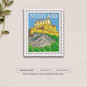 May include: A rectangular embroidered patch shaped like a postage stamp featuring a yellow castle on a rocky hill under a blue sky with the word SCOTLAND in white text. Below the patch, text reads BACKING OPTIONS: SEW ON PATCH or IRON ON PATCH.