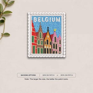 May include: A rectangular embroidered patch shaped like a postage stamp featuring a row of colorful buildings in Belgium. The design includes red, orange, and pink facades against a blue sky with the word BELGIUM printed in white at the top.
