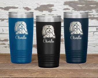 May include: Three stainless steel tumblers with a white dog silhouette and the name "Charlie" engraved on each. The tumblers are in blue, black, and navy blue.