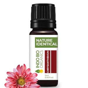 May include: A brown glass bottle of Indo Bio Organics Chrysanthemum essential oil. The bottle is labelled "Nature Identical" and contains 15 ml (0.50 fl oz) of oil. A pink chrysanthemum flower is in the foreground.
