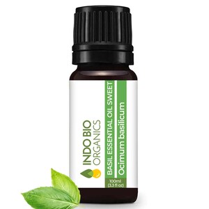 May include: A dark brown glass bottle with a black cap, labelled "INDO BIO ORGANICS BASIL ESSENTIAL OIL SWEET Ocimum basilicum 100ml (3.3 fl oz)". The bottle is sitting on a white background with two green basil leaves.