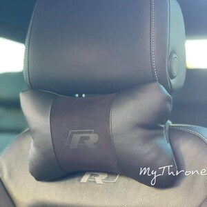 May include: Black leather car seat with a black headrest and a black pillow with an embroidered "R" logo. The pillow is positioned on top of the headrest. The text "my Throne" is visible in the lower right corner of the image.