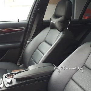 May include: Black leather car seats with a black headrest pillow that says "Mercedes Benz" on it.