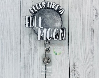 May include: A silver glitter badge holder with a black and white moon design. The text "Feels Like A Full Moon" is written on the badge holder.
