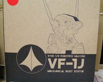 May include: A cardboard box with a line drawing of a robot on the front. The box is brown with black text that reads "ST06 1/8 ROBOTECH VALKYRIE VF-1J MECHANICAL BUST STATUE ROBOTECH".