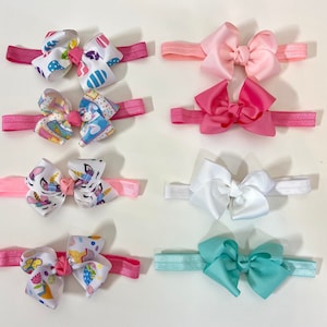 May include: Set of ten colorful hair bows with elastic headbands. The bows are made of satin ribbon and feature various patterns, including unicorns, Easter eggs, and solid colors like pink, white, and teal.