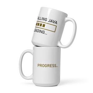 Op de afbeelding: Twee witte keramische mokken, de ene op de andere gestapeld. De bovenste mok heeft de tekst "INSTALLING JAVA" met een laadbalk. De onderste mok heeft het woord "PROGRESS..." in goudkleur gedrukt. Beide mokken hebben een gebogen handvat.