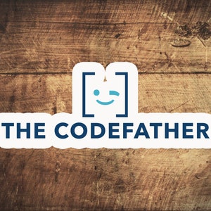 Puede incluir: Una pegatina blanca con el texto "THE CODEFATHER" en azul oscuro, sobre un fondo de madera. La pegatina presenta un logotipo estilizado con corchetes y una cara guiñando un ojo.
