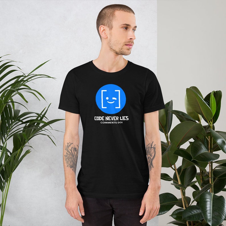 May include: A black t-shirt with a blue circle containing a white winking face inside square brackets. The text "CODE NEVER LIES COMMENTS DO" is printed below the circle.