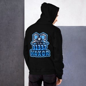 May include: Black hooded sweatshirt with a blue and white graphic on the back. The graphic features a hooded figure and the text "31337 H4XOR" in a stylized font. The sweatshirt is made of a soft material.