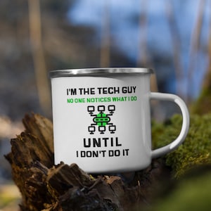 Pode incluir: Caneca de esmalte branco com um design preto e verde. A caneca tem uma alça preta e o texto "Eu sou o cara da tecnologia. Ninguém percebe o que eu faço até que eu pare de fazer." O design inclui uma imagem estilizada de uma rede de computadores.