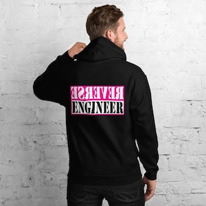Könnte beinhalten: Schwarzer Kapuzenpullover mit einem pinkfarbenen Rechteck auf der Rückseite, auf dem in weißen Buchstaben "REVERSE ENGINEER" steht.