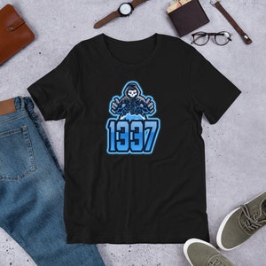 May include: Black t-shirt with a blue and white graphic of a hooded figure with a skull face, giving a thumbs up on each hand. The text "1337" is below the figure.