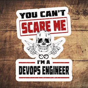 Könnte beinhalten: Weißer Aufkleber mit schwarzem Text, der "You can't scare me I'm a DevOps Engineer" lautet. Der Aufkleber zeigt außerdem einen Schädel mit gekreuzten Blitzen und einen roten Stempel mit der Aufschrift "Scare Me".