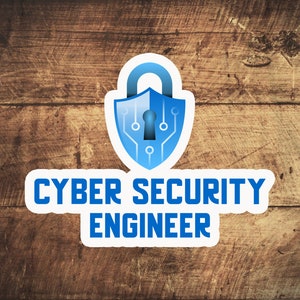 May include: A blue and white sticker with a padlock icon and the text "Cyber Security Engineer". The sticker is on a brown wooden background.