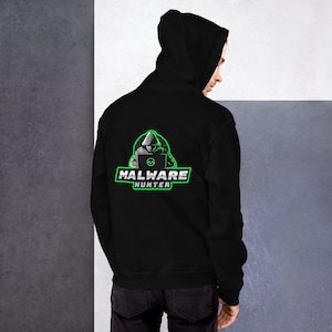 Może przedstawiać: Czarna bluza z kapturem z zielono-białą grafiką na plecach. Grafika przedstawia postać w kapturze pracującą na laptopie z napisem "MALWARE HUNTER" w zielonym kolorze.