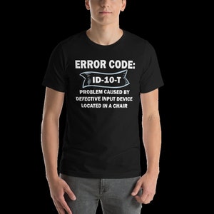 Peut inclure: T-shirt noir avec du texte blanc qui dit "ERROR CODE: ID-10-T PROBLEM CAUSED BY DEFECTIVE INPUT DEVICE LOCATED IN A CHAIR"