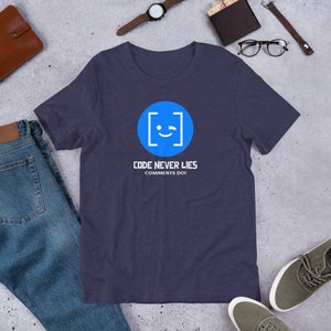 May include: A navy blue t-shirt featuring a white graphic of a blue circle with a winking face inside square brackets. The text "CODE NEVER LIES COMMENTS DO" is printed below the graphic.