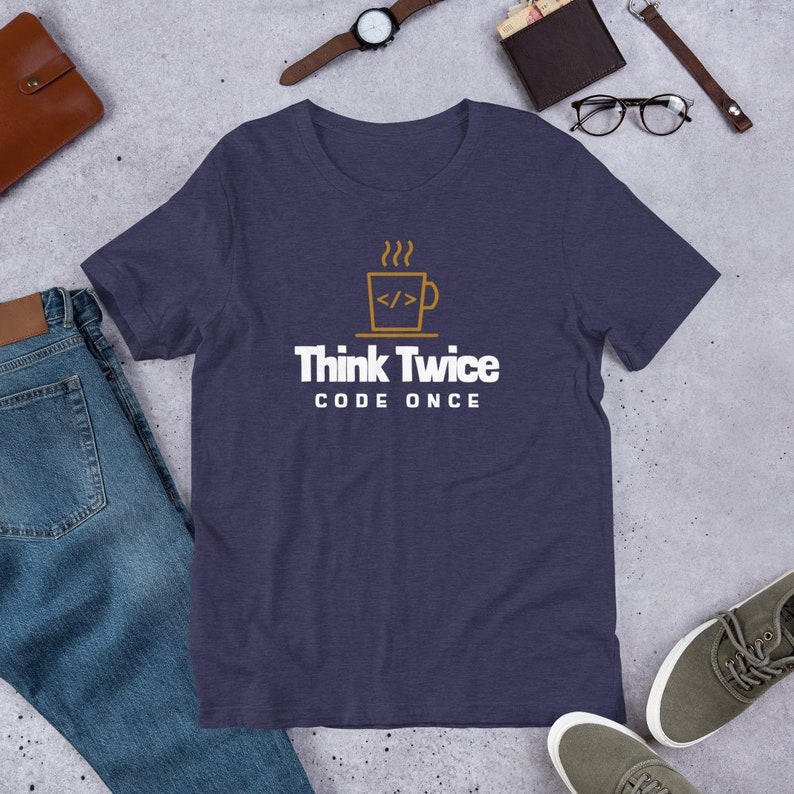 May include: A navy blue t-shirt featuring a white graphic of a coffee cup with steam rising from it. The cup contains code symbols. The text "Think Twice Code Once" is printed below the cup.