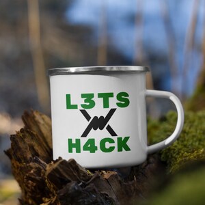 Könnte beinhalten: Weiße Emaille-Campingtasse mit einer schwarzen und grünen Grafik. Die Grafik sagt "L3TS H4CK" mit einem Stacheldraht-Design.