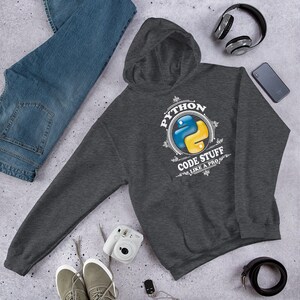 May include: A dark grey hooded sweatshirt with a white graphic design featuring the Python logo and the text "Python Code Stuff Like A Pro".