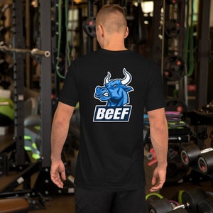 Puede incluir: Camiseta negra con un gráfico de cabeza de toro azul y la palabra "BEEF" impresa en la espalda.