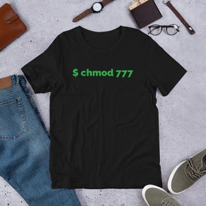 Könnte beinhalten: Schwarzes T-Shirt mit einem grünen Dollarzeichen und dem Text "chmod 777" auf der Vorderseite.