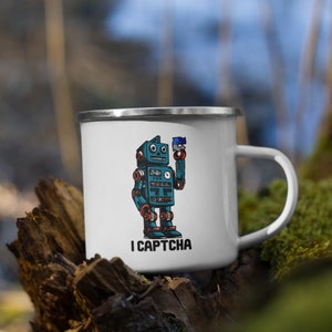 May include: White enamel mug with a blue robot holding a blue and white captcha icon. The mug has the text "I CAPTCHA" printed on the front.