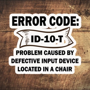May include: A white sticker with black text that reads "ERROR CODE: ID-10-T PROBLEM CAUSED BY DEFECTIVE INPUT DEVICE LOCATED IN A CHAIR". The sticker is on a brown wooden surface.
