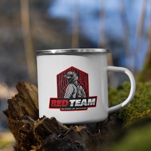 Peut inclure: Mug de camping en émail blanc avec un logo rouge et noir représentant un personnage masqué et le texte "RED TEAM DEFENSE BY OFFENSE".