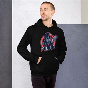 May include: Black hooded sweatshirt with a graphic of a woman wearing sunglasses and holding a weapon. The graphic is in a circle with the text "CYBER MILITIA" below it.