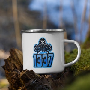 May include: White enamel camping mug with a blue and white graphic of a hooded figure with a skull face and the text "1997".