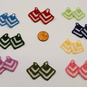 May include: A selection of colourful, handmade crochet potholders. The potholders are square-shaped with a chevron pattern in white, and come in shades of blue, red, green, yellow, pink, and dark green. Each has a small loop.