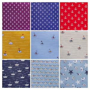 May include: Nine fabric swatches with nautical themes. The swatches feature anchors, sailboats, paper boats, and seagulls. The fabrics are in various colours, including blue, red, yellow, and white.