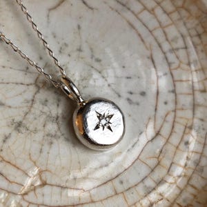 A recycled silver hand forged round pendant featuring a hand engraved star with 1.5mm lab grown diamond set in the centre. An ideal gift for the North Star in your life.