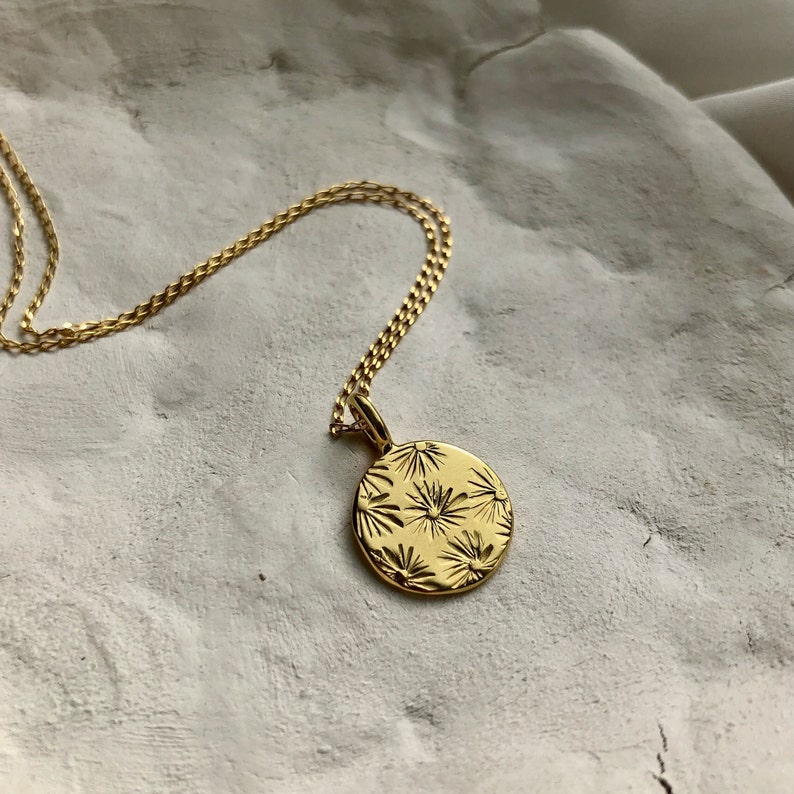 A gold vermeil disc pendant with a hand embossed sunbeam motif. The pendant is hung from a fine gold vermeil, diamond cut curb chain.
