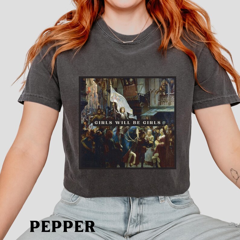 May include: A charcoal gray cropped t-shirt with a graphic print of a painting. The painting depicts a group of people in a historical setting. The text "Girls Will Be Girls" is printed on the graphic.