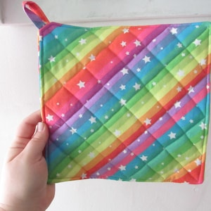 May include: Rainbow-colored pot holder with white stars. The pot holder is quilted and has a loop for hanging.